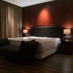Kamar tidur utama rumah di Kelapa Gading dengan dinding panel kayu dan tirai gelap