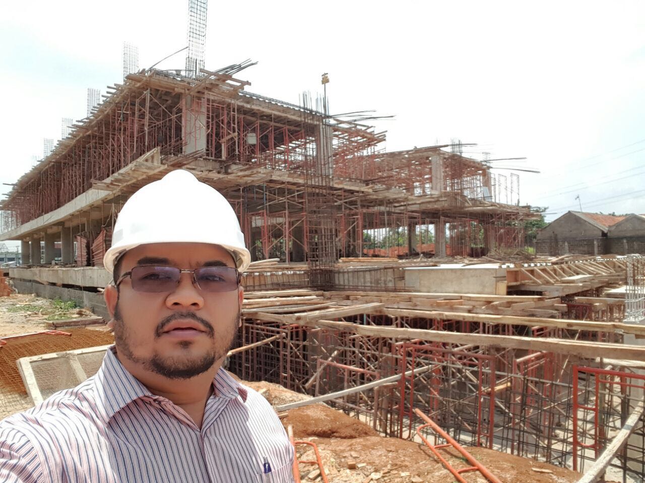 Ir. Jonathan Togi, MT, Komisaris PT. Baja Trikarsa Persada, mengenakan helm proyek di depan bangunan yang sedang dikerjakan